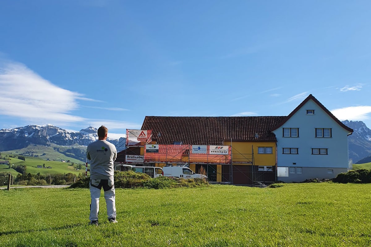Sacha Dähler steht vor einem Haus, das er gestrichen hat